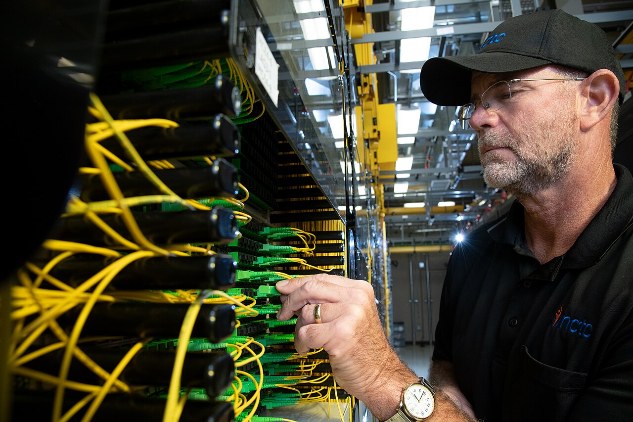 A technician connecting fiber-optic equipment inside a data center