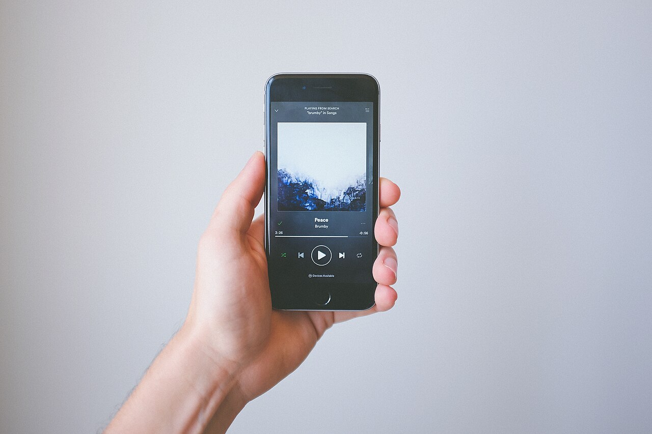 De Spotify‑app staat open op een smartphone naast een koptelefoon.
