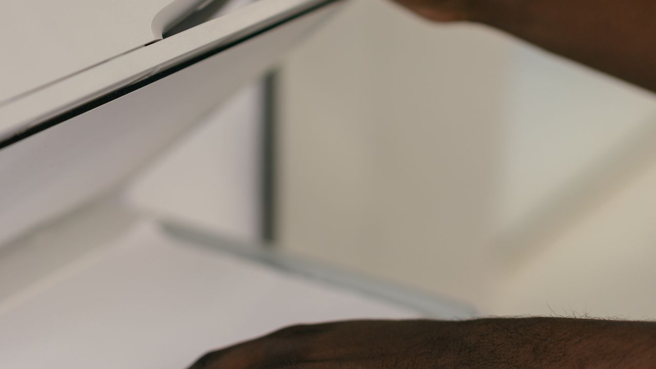 Des mains ajustent un document sur le plateau d'un scanner dans un bureau