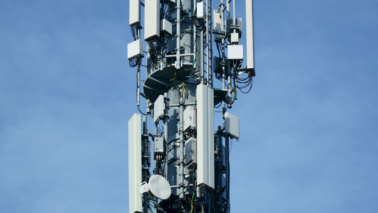Een telecommunicatiemast met meerdere antennes tegen een blauwe lucht
