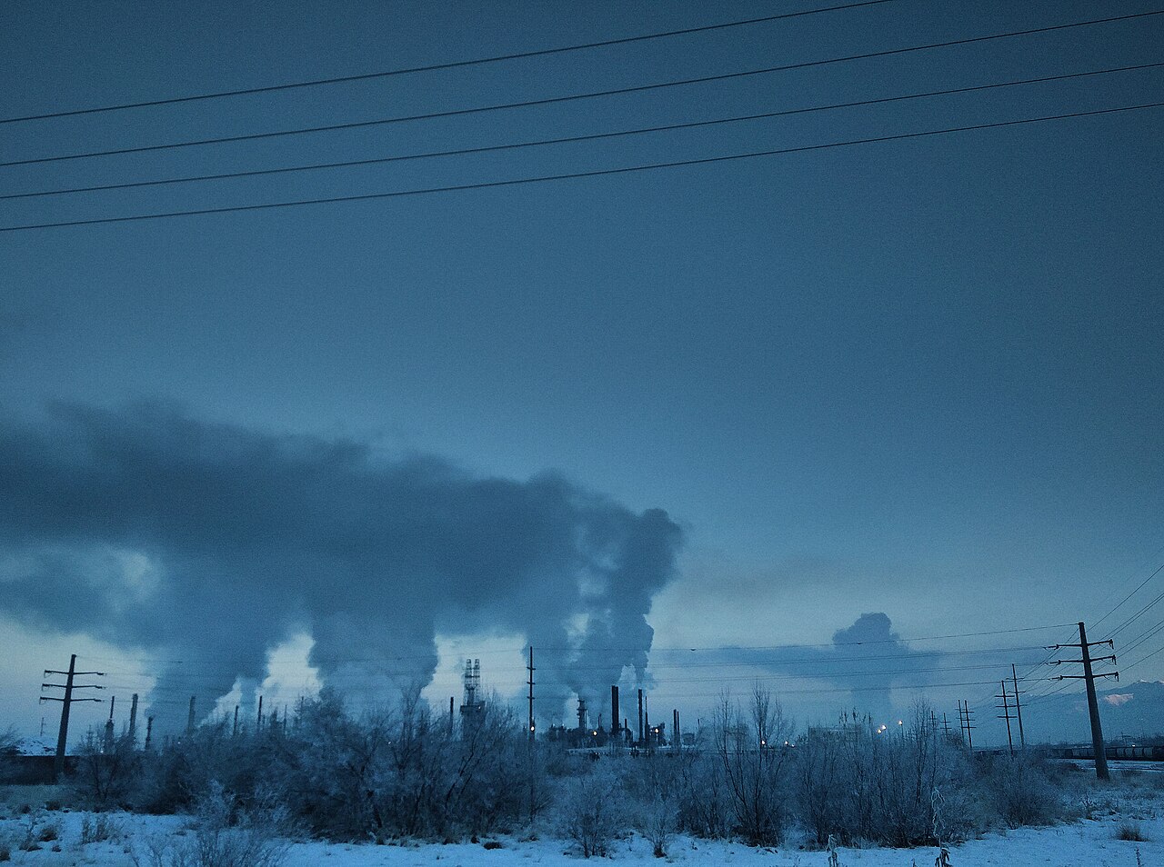 Industrial smokestacks releasing emissions into the sky at dusk