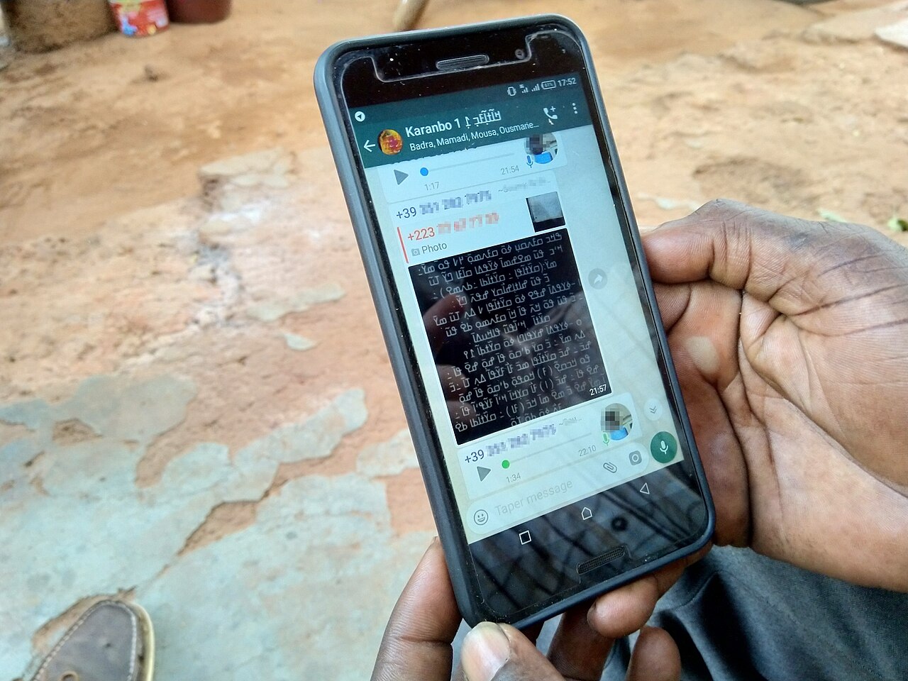 Personne tenant un smartphone affichant une classe WhatsApp