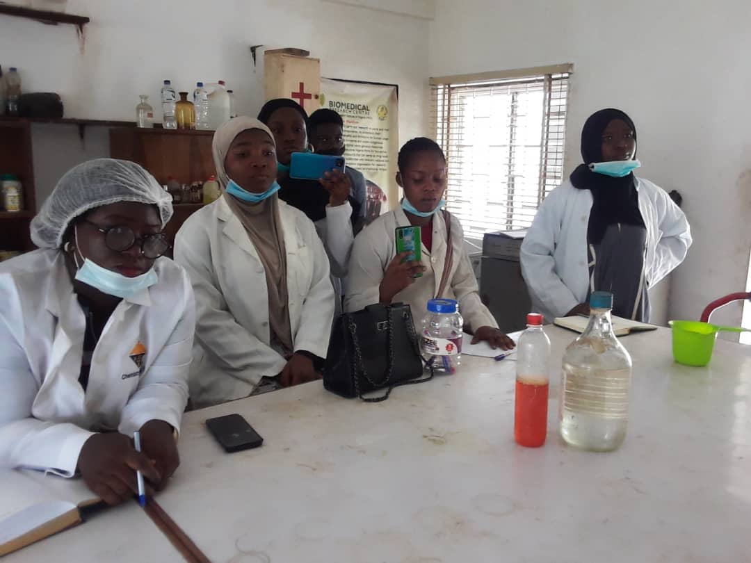 Cinq scientifiques en blouse blanche de laboratoire se tiennent autour d'un plan de travail dans un laboratoire biomédical.