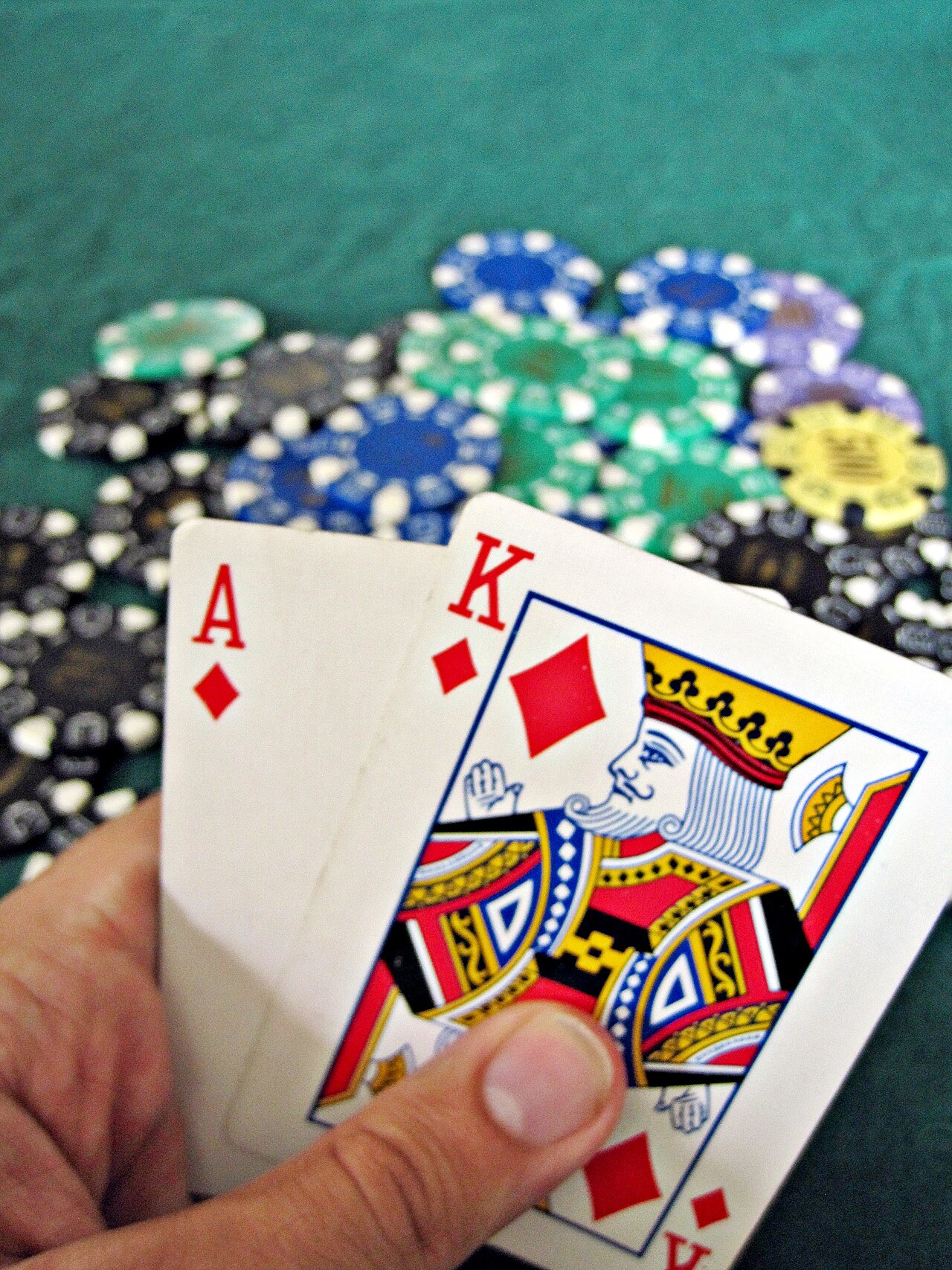 Eine Draufsicht auf einen grünen Blackjack-Tisch mit ausgeteilten Spielkarten, Casino-Chips und Setzfeldern.